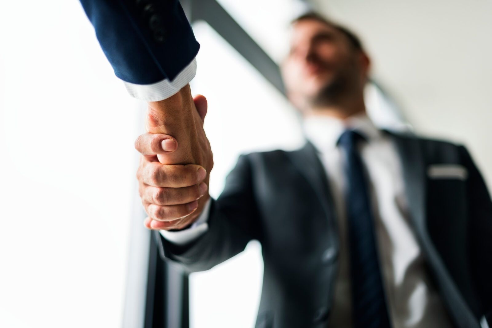 Two people in suits shaking hands, close up