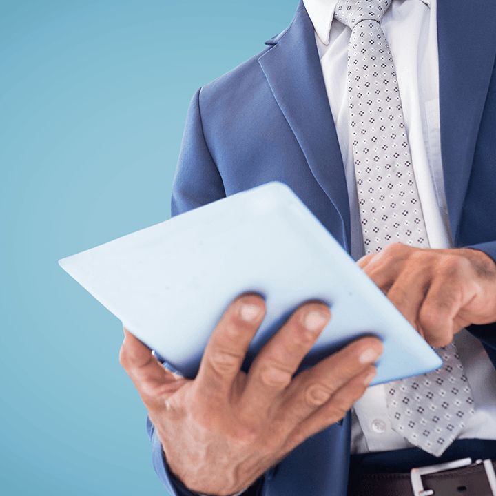 A man in a suit holding a tablet and tapping its screen